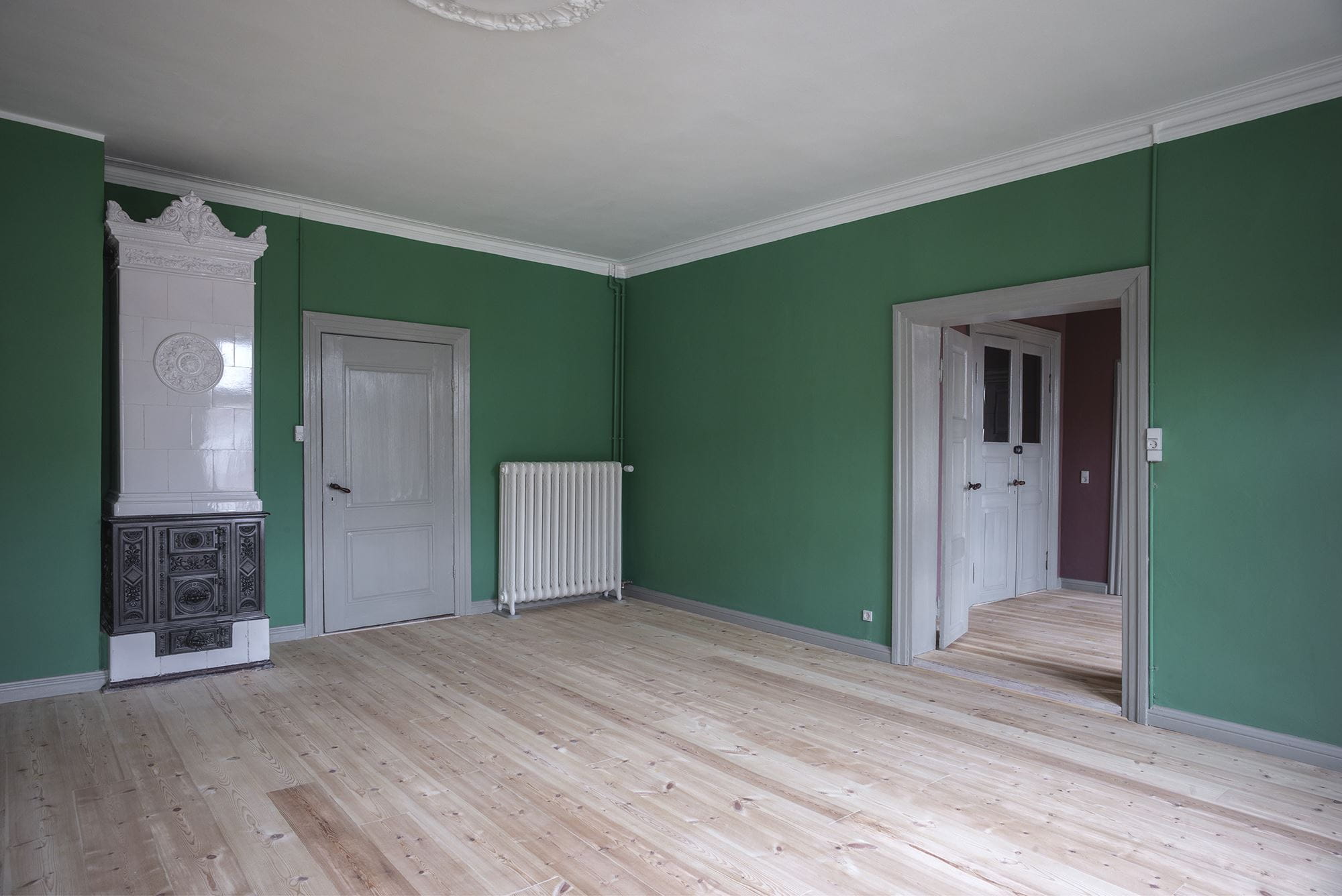 Den grønne stue ligger på førstesal i forhuset i Marcussens Gård. Den gamle kakkelovn er i dag kun til pynt.