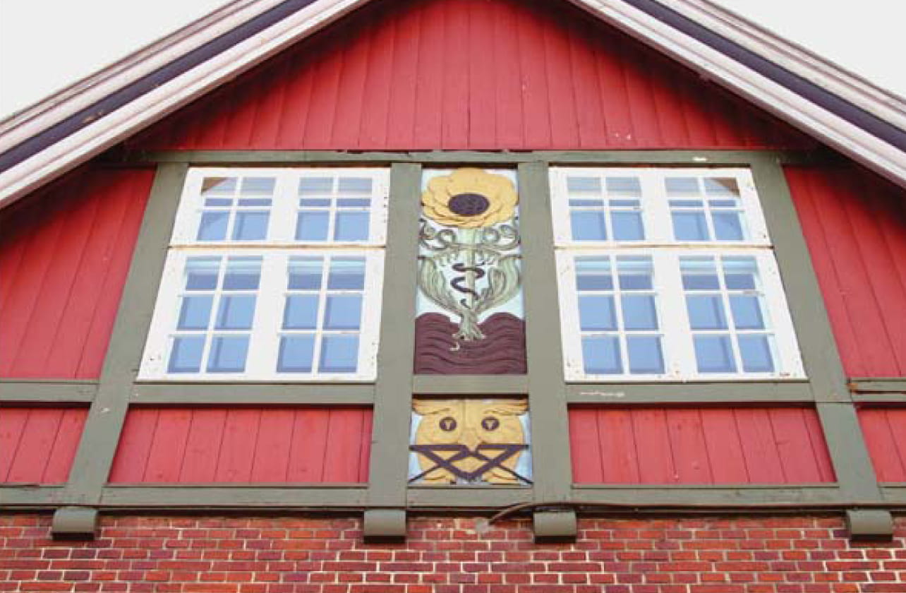 men meget helstøbt og med en overdådig mængde detaljer. Kviste og gavle har bindingsværk og malede partier med solsikker og ugler i et formsprog inspireret af gammel nordisk ornamentik.